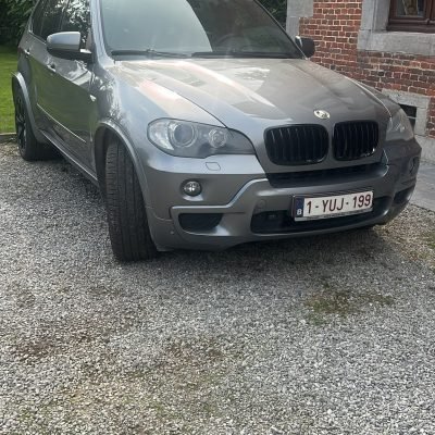 BMW X5 grise de 2010 stationnée devant une maison